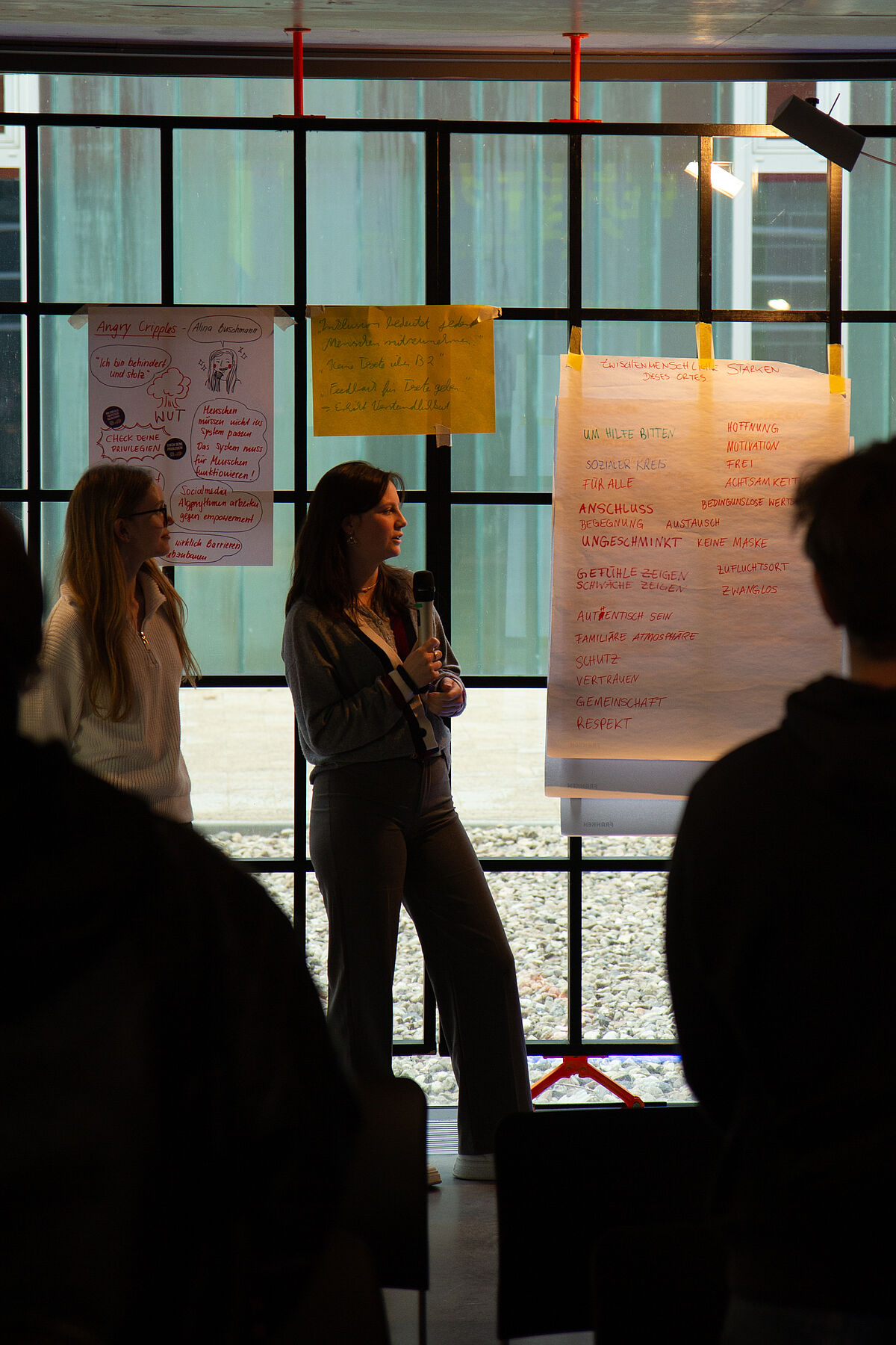 Zwei Personen stehen vor der Gruppe und berichten über die Inhalte und Ergebnisse ihres Workshops während der Postersession.