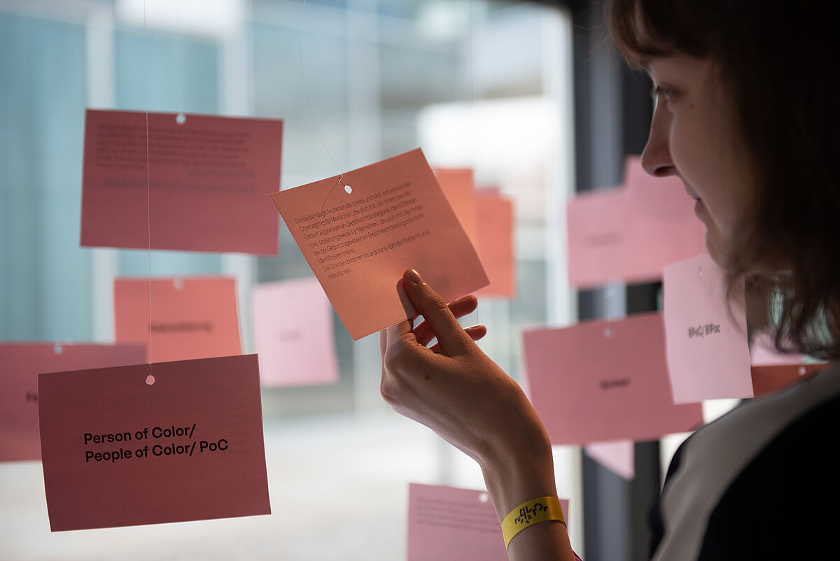 Mehrere Zettel mit Begriffen und Definitionen zum Thema Inklusion und Exklusion hängen von der Decke herunter und konnten von Festivalbesucher*innen in den Pausen gelesen werden.