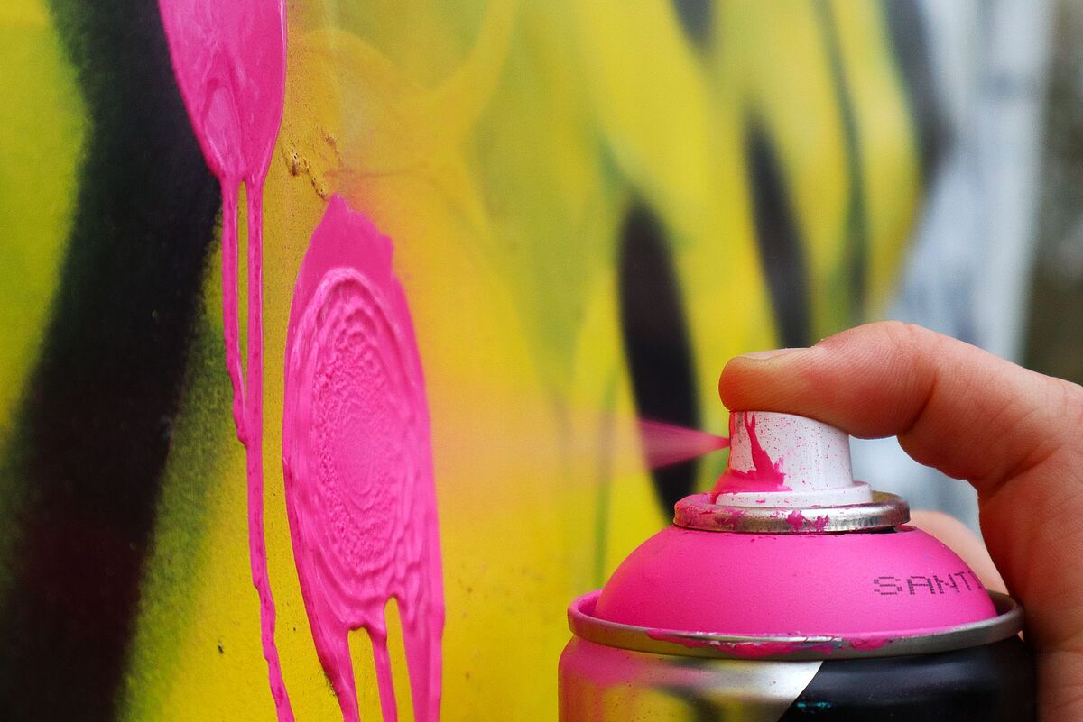 Nahaufnahme einer pinken Sprühdose, mit der Farbe auf eine Wand gesprüht wird – aufgenommen im Graffiti-Workshop.