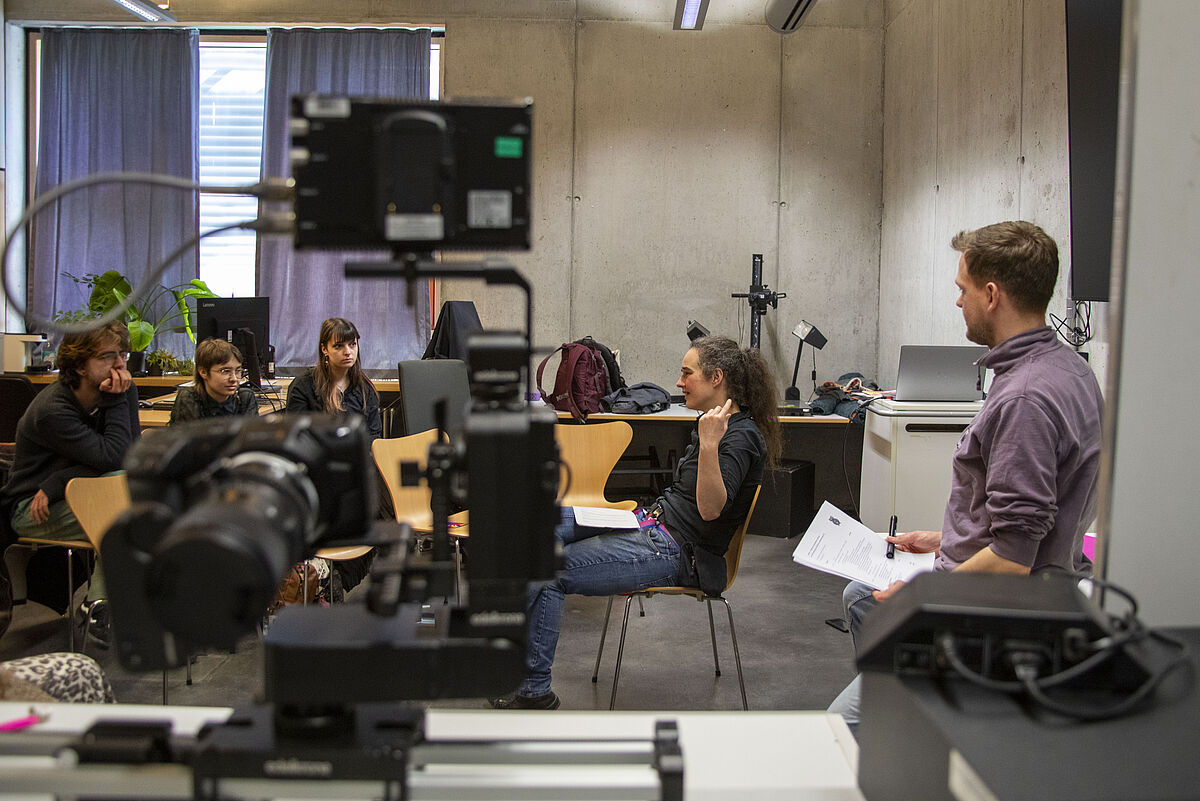 Teilnehmende sitzen im Raum und schauen Kurzfilme, anschließend tauschen sie sich über die Inhalte aus.