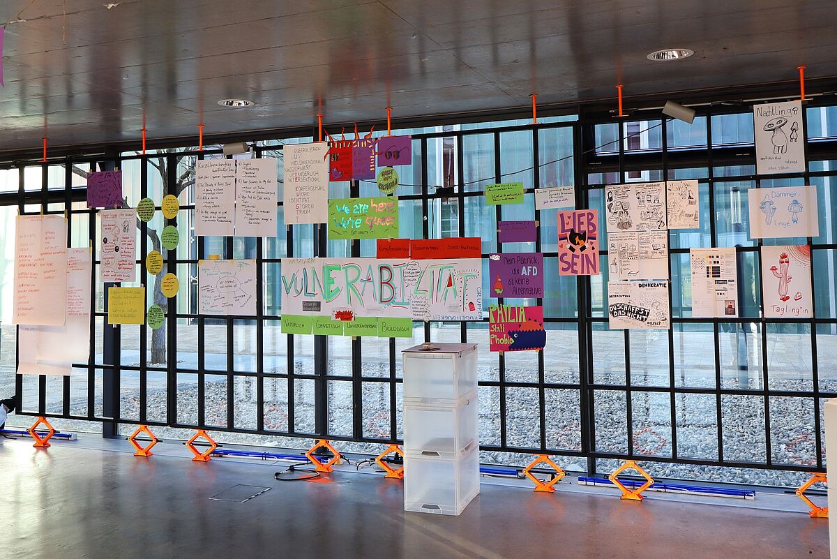 Eine Wand mit ausgehängten Postern und Präsentationen, die die Ergebnisse der verschiedenen Workshops des Festivals zeigen.