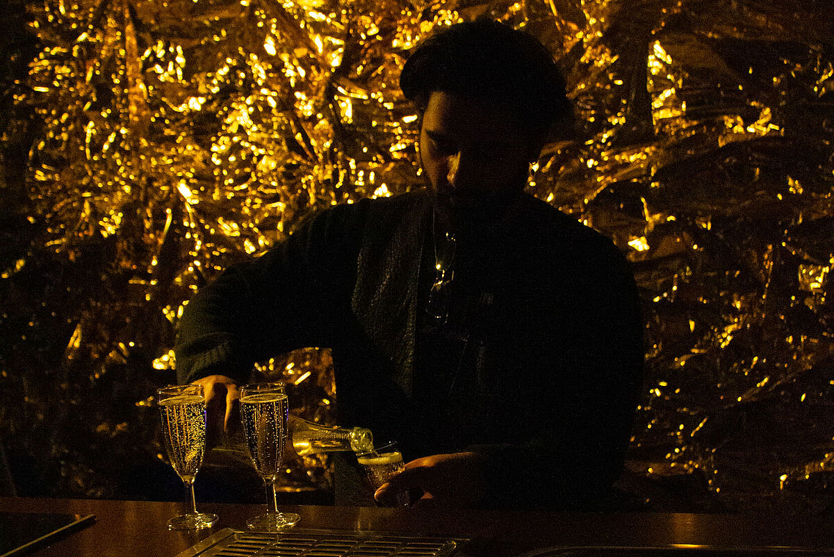 Ein Barkeeper steht hinter der Bar und schenkt während des Festival-Ausklangs Getränke aus.