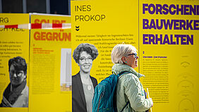 Die Frau steht ganz nah an einer Stele und liest.