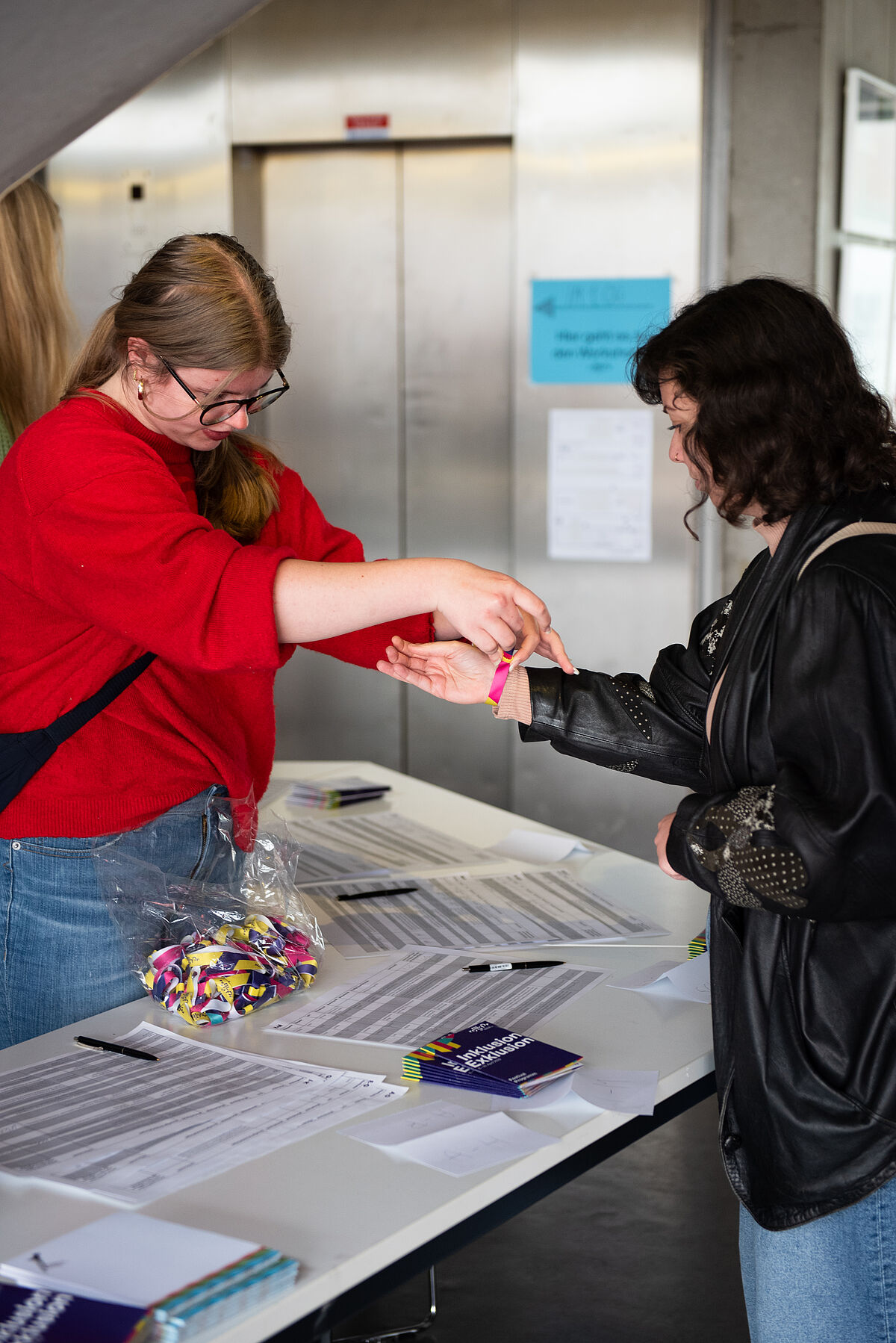 Eine Person bekommt an der Anmeldung ein Festivalbändchen ans Handgelenk gemacht.
