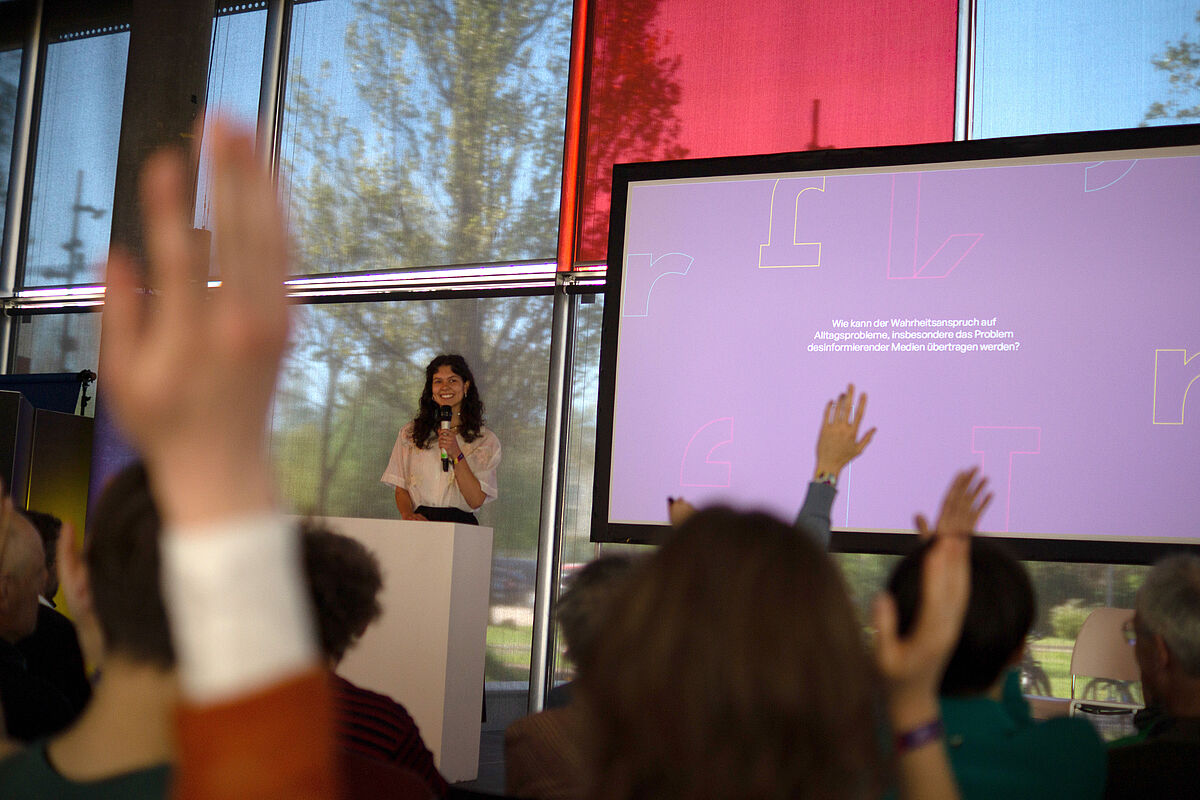 Studentin hält Vortrag vor Menschenmenge