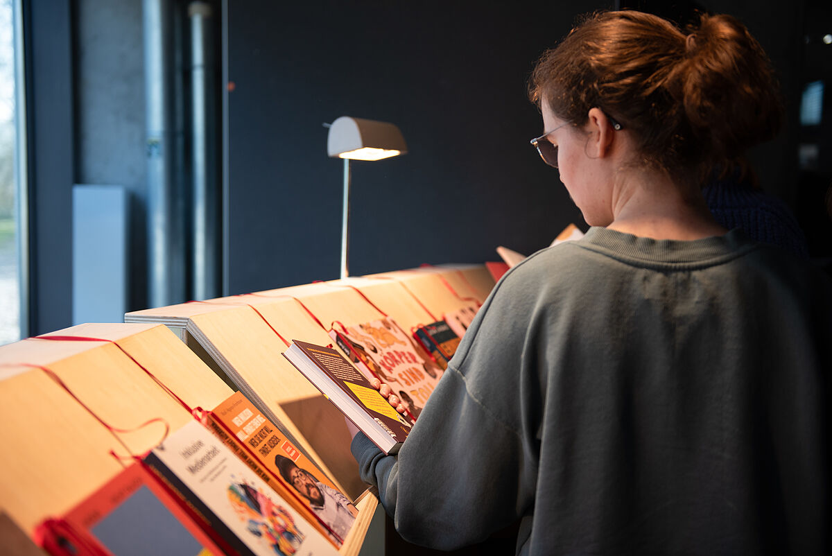 Eine Festivalbesucherin schaut sich Bücher an einem Stand mit inklusionsbezogener Literatur an.