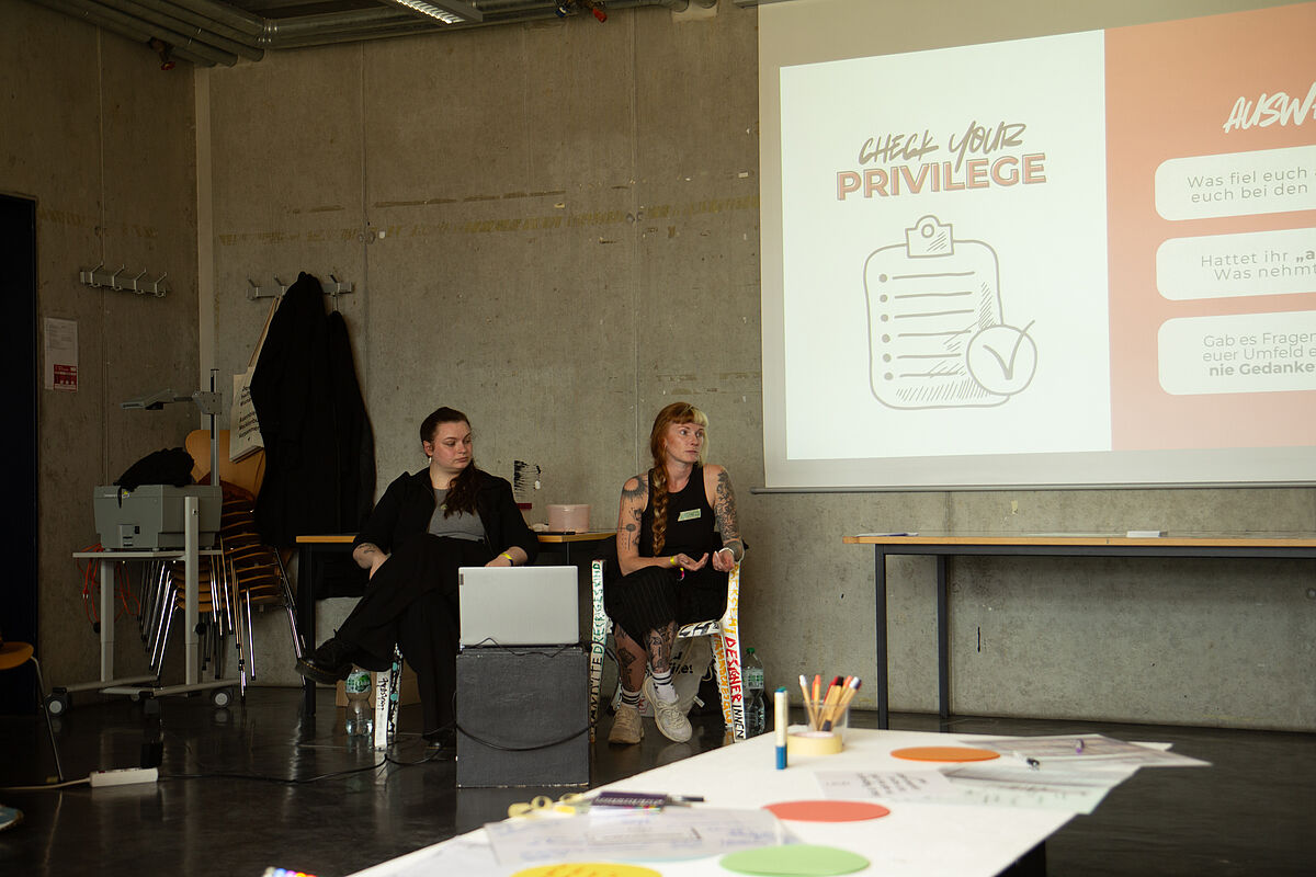 Any und Kathi sitzen vor einer Präsentation und bereiten sich auf ihren Workshop "Awareness im Alltag: Miteinander bewusst gestalten" vor.